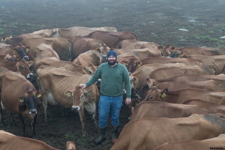 Oregon dairy farmer stands in a pasture of dairy cattle on his Oregon farm